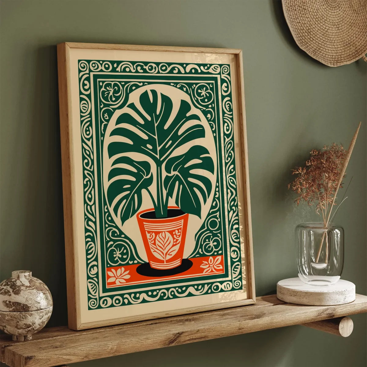 Framed artwork of a plant on a wooden shelf against a green wall.