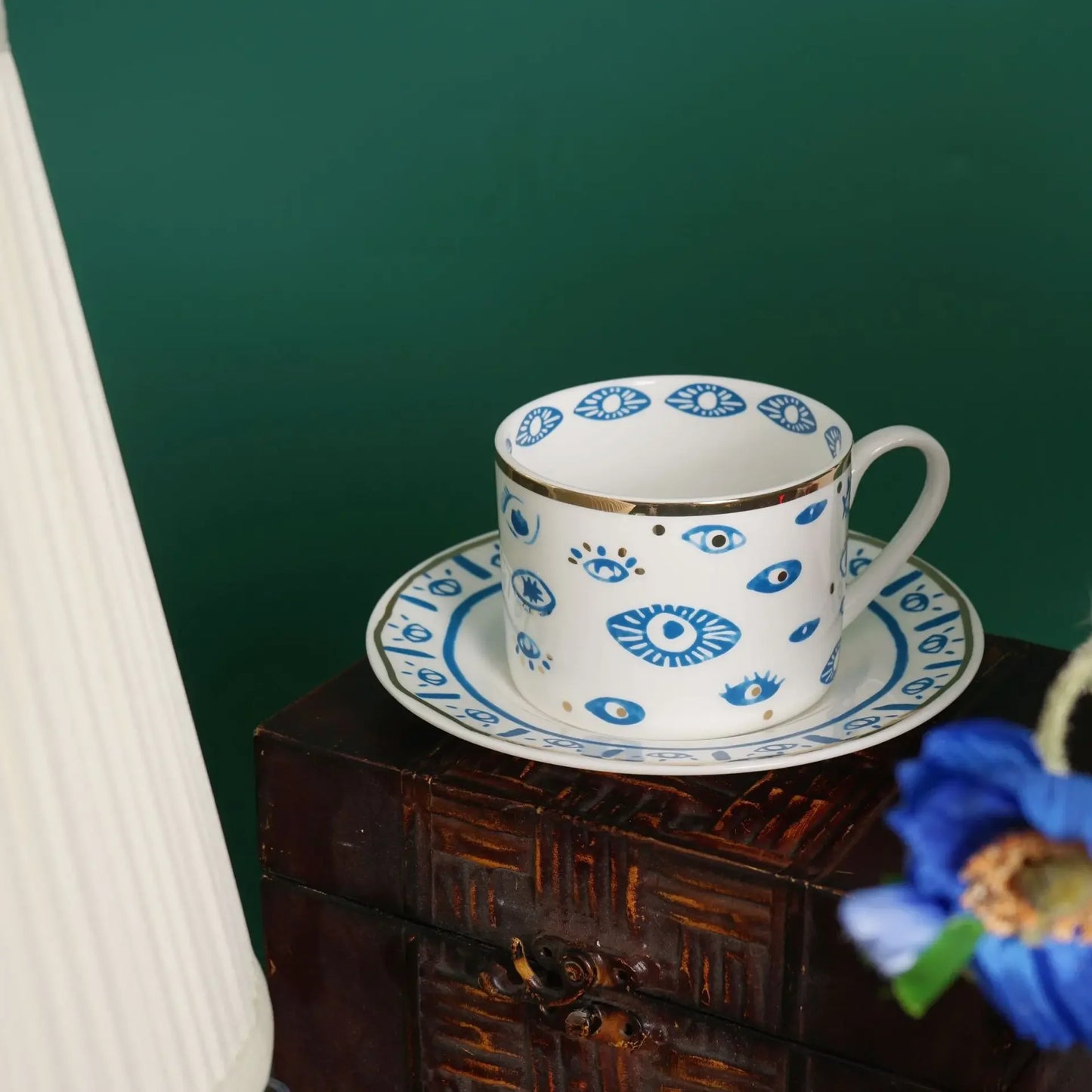 Ceramic cup and saucer with blue floral patterns on a wooden surface against a green wall.