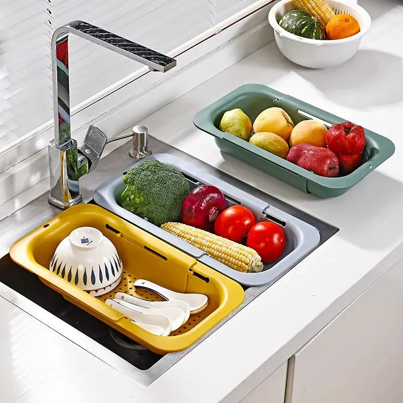 Kitchen sink with yellow and gray drain baskets containing vegetables and kitchen tools.