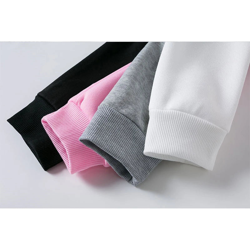 Four folded sweaters in black, pink, gray, and white on a light gray background