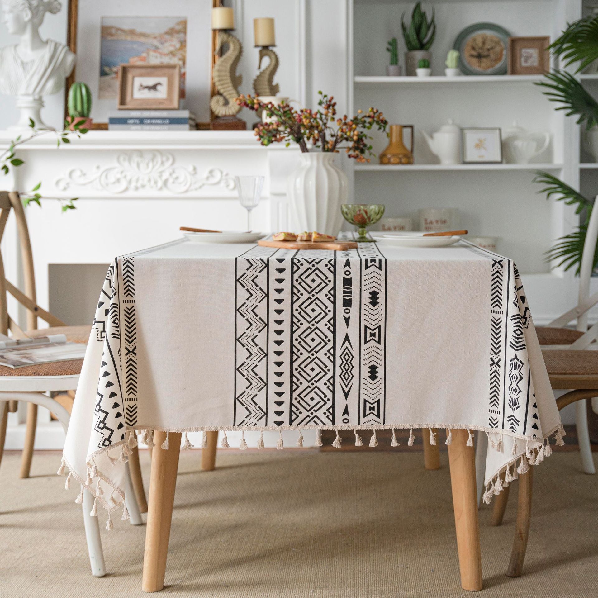 Dining room with a table covered by a patterned tablecloth, surrounded by chairs and decor.
