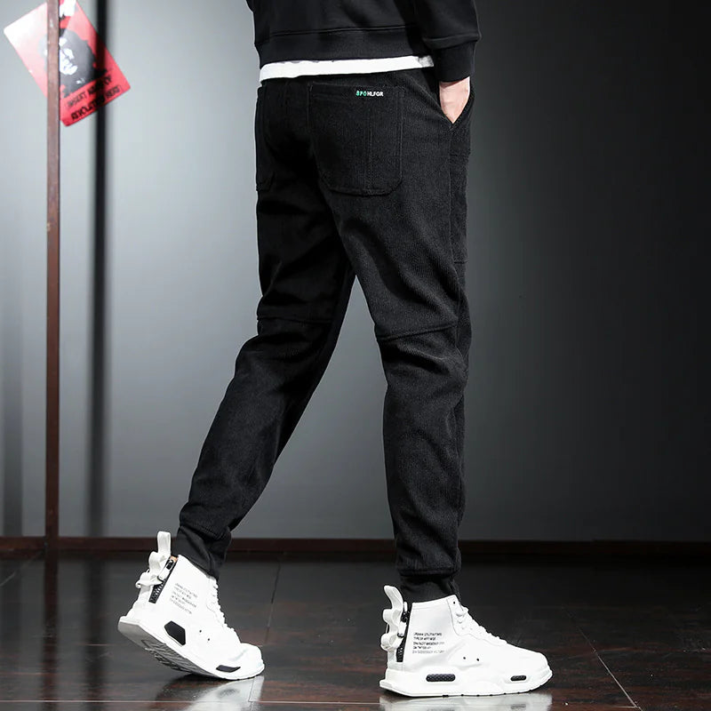 Person wearing black pants and white sneakers in a minimalistic setting
