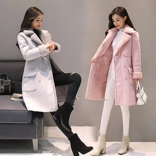 Two women wearing long coats, one gray and one pink, in a showroom setting.