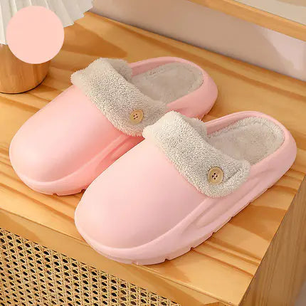 Pair of pink slippers with gray lining on a wooden surface