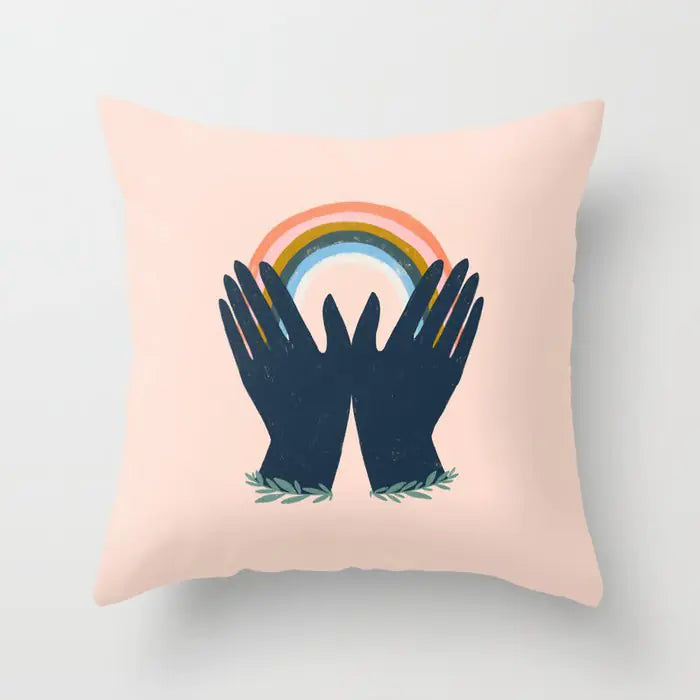 Pillow with hands holding a rainbow design on a light pink background