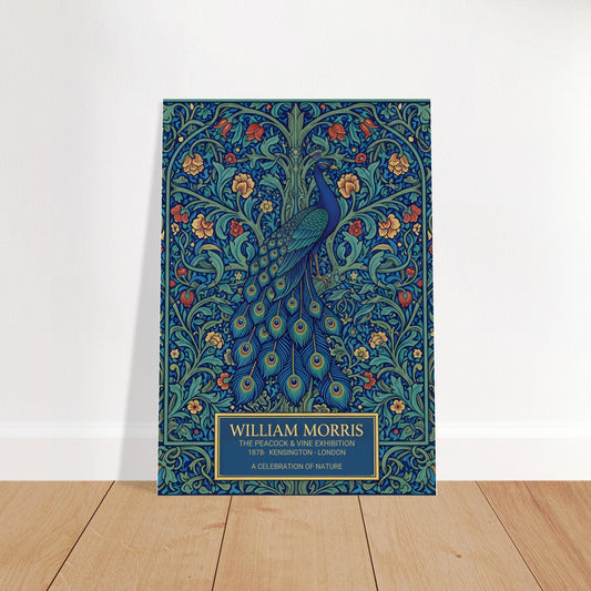 Vintage William Morris exhibition poster of a blue peacock with a long, detailed tail, surrounded by intricate green vines and orange flowers on a dark teal background. Cream-colored text at the bottom reads William Morris The Peacock and Vine Exhibition.
