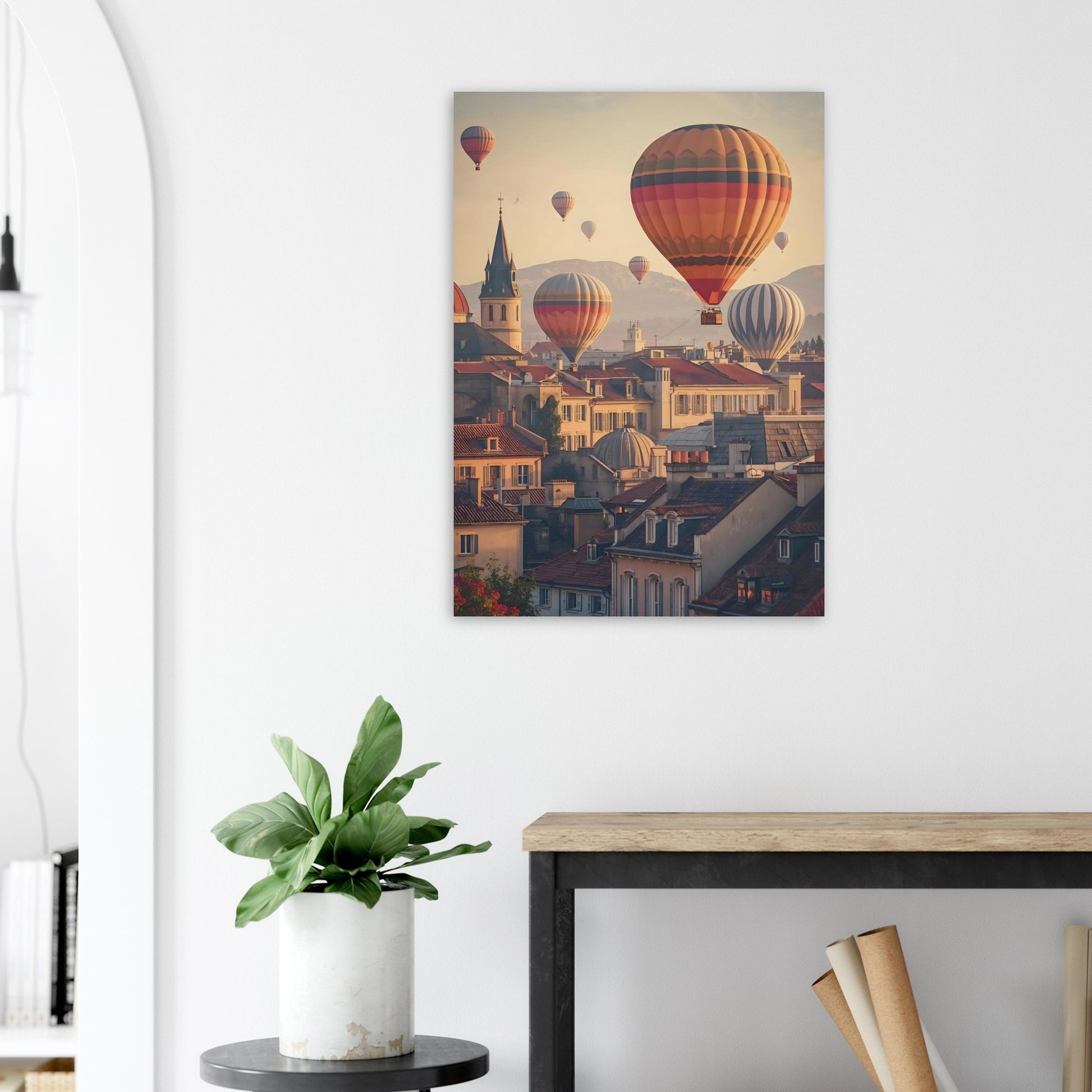 Canvas print of hot air balloons over a town hanging on a white wall above a desk.