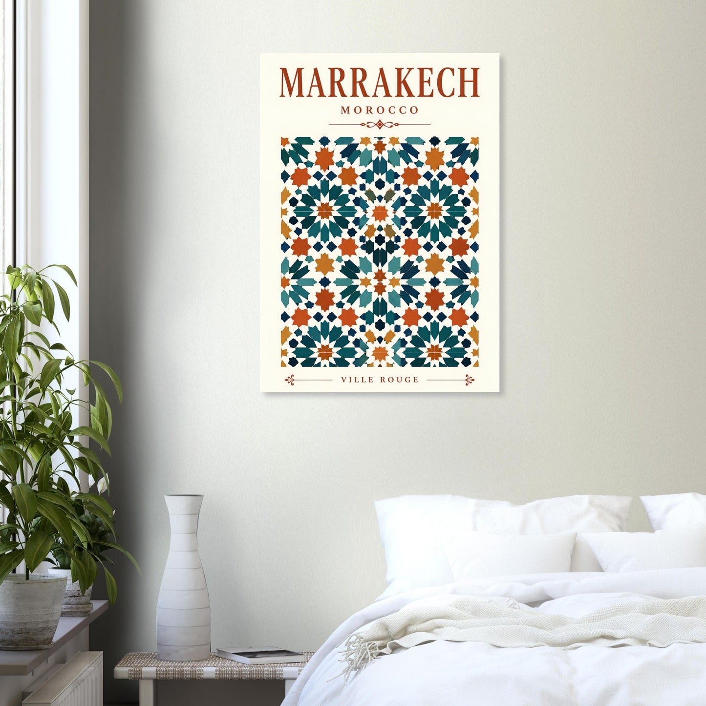 A framed wall art print featuring a Moroccan tile pattern with the text 'MARRAKECH MOROCCO' and 'VILLE ROUSE' hangs on a light gray wall above a bed in a styled bedroom.