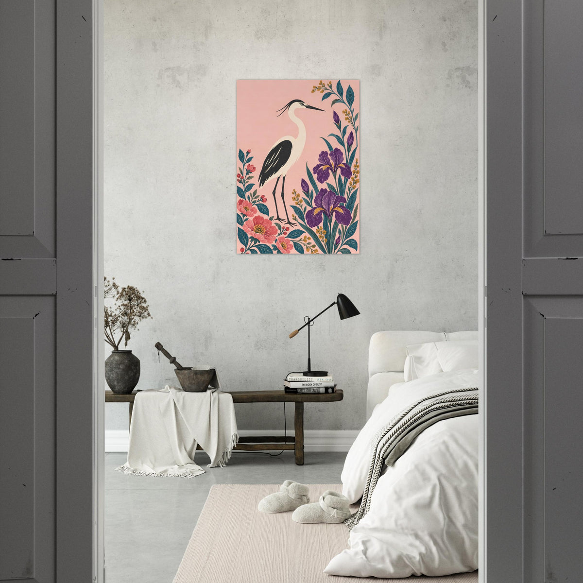 A vertical art print featuring a stylized pink heron surrounded by colorful flowers, displayed on a textured gray wall in a modern bedroom setting.
