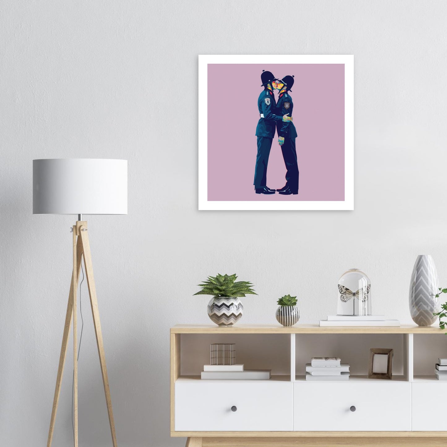 Framed artwork of a person in a blue outfit on a pink background, displayed in a room with a lamp and shelves.