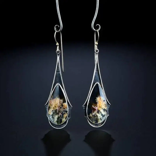 Long dangle earrings with silver wire frame and multicolored marble glass teardrop design on a dark reflective background