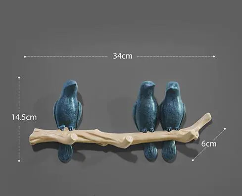 Three blue bird figurines on a branch with measurements indicated.