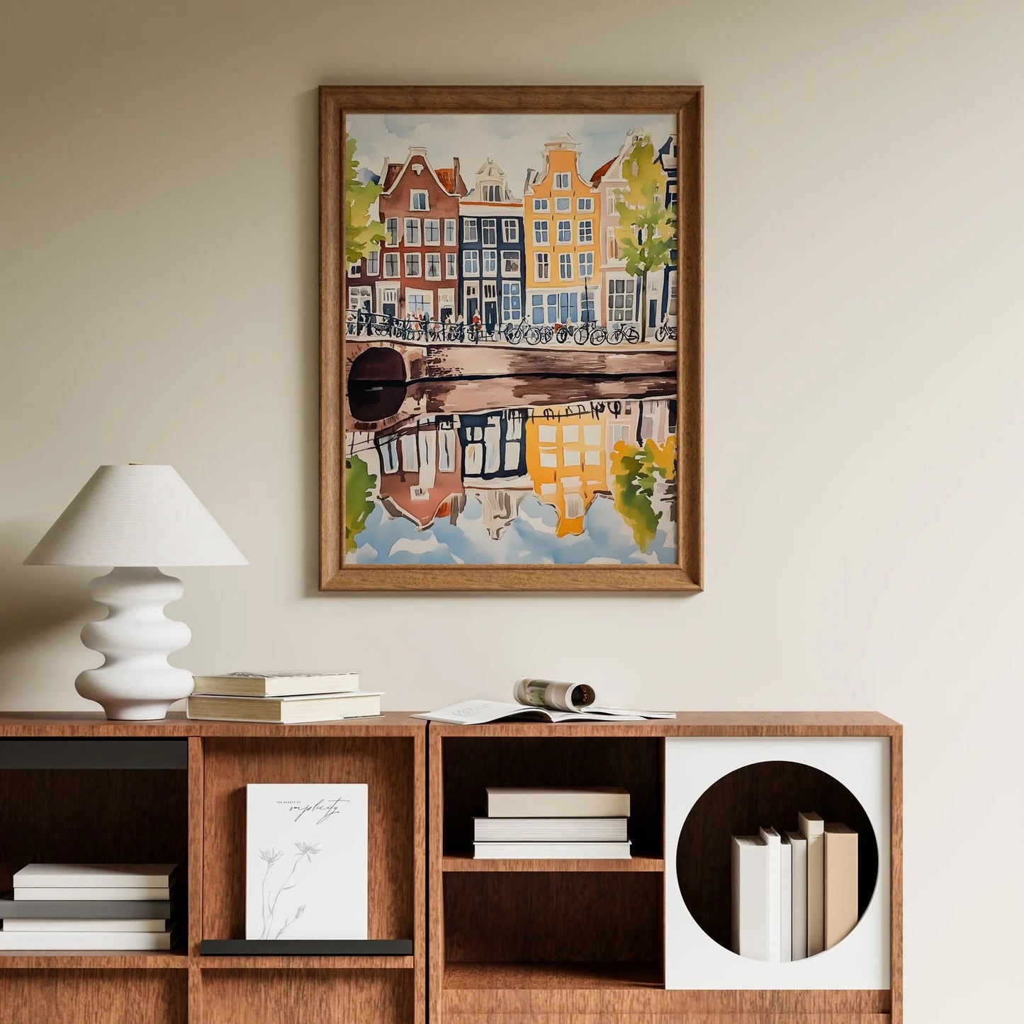 Framed artwork of a canal scene above a wooden shelf with books and decor.