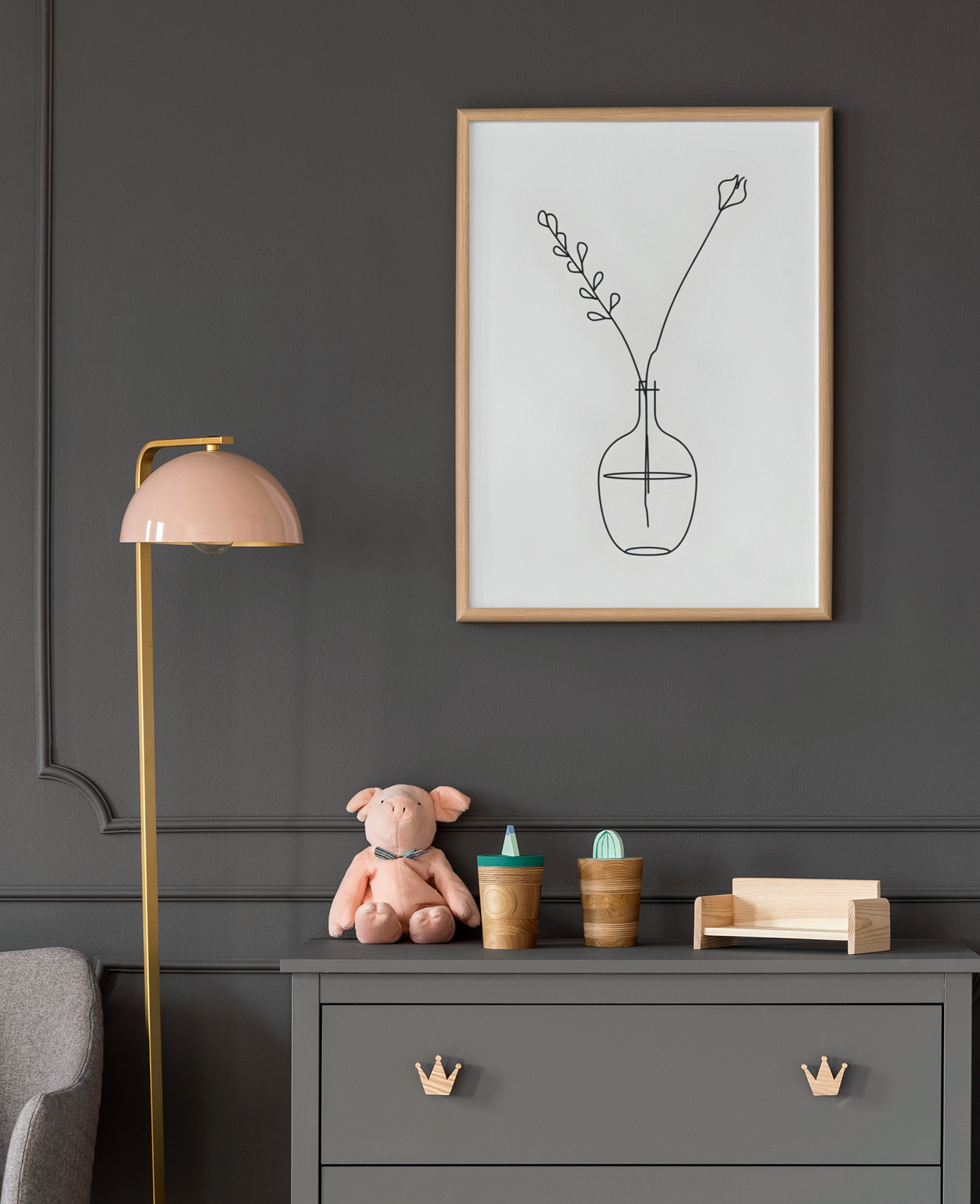 Framed minimalist artwork on a dark wall above a dresser with toys and decor items.