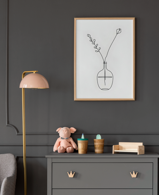 Framed minimalist artwork on a dark wall above a dresser with toys and decor items.