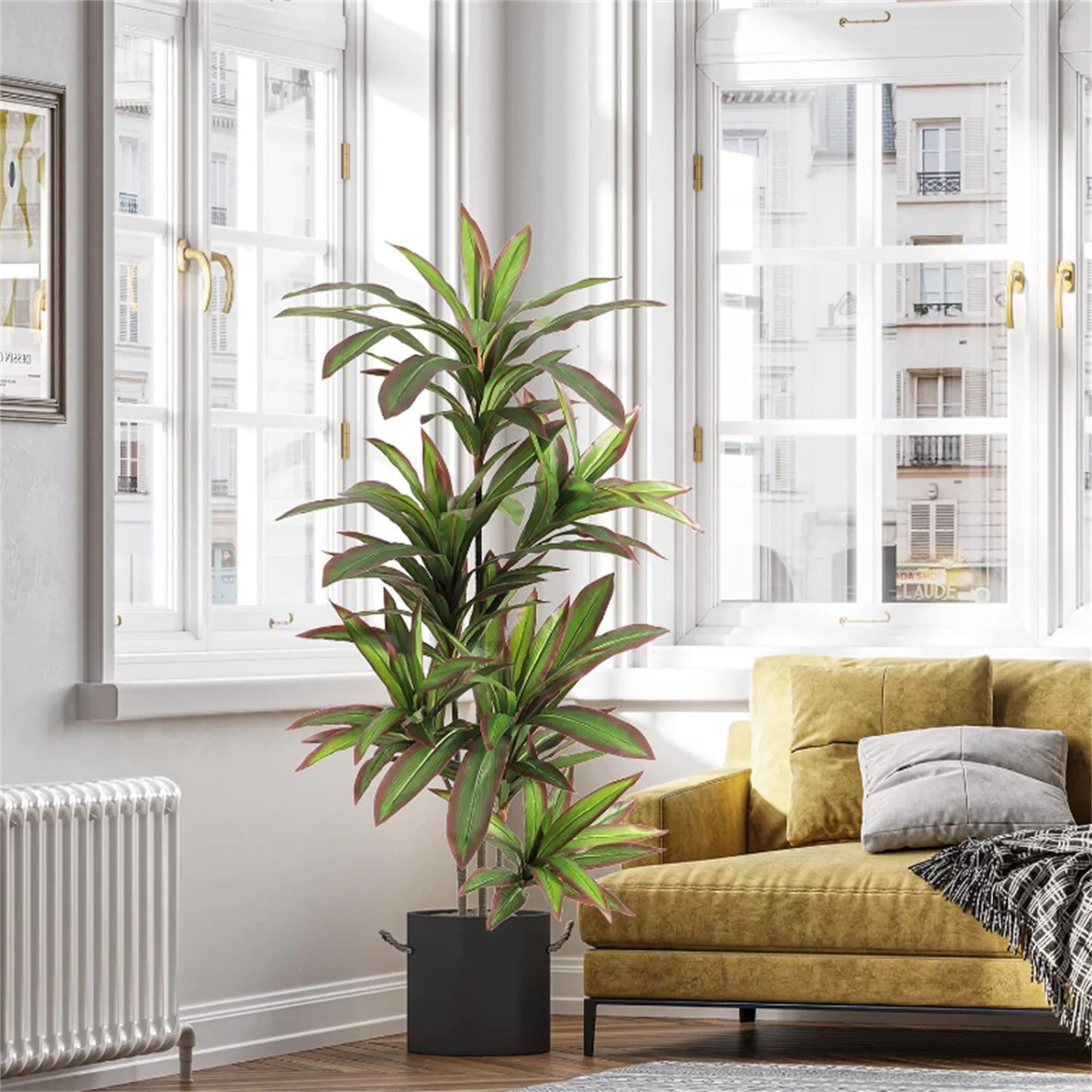 Green potted plant in a living room with a yellow sofa and large windows.