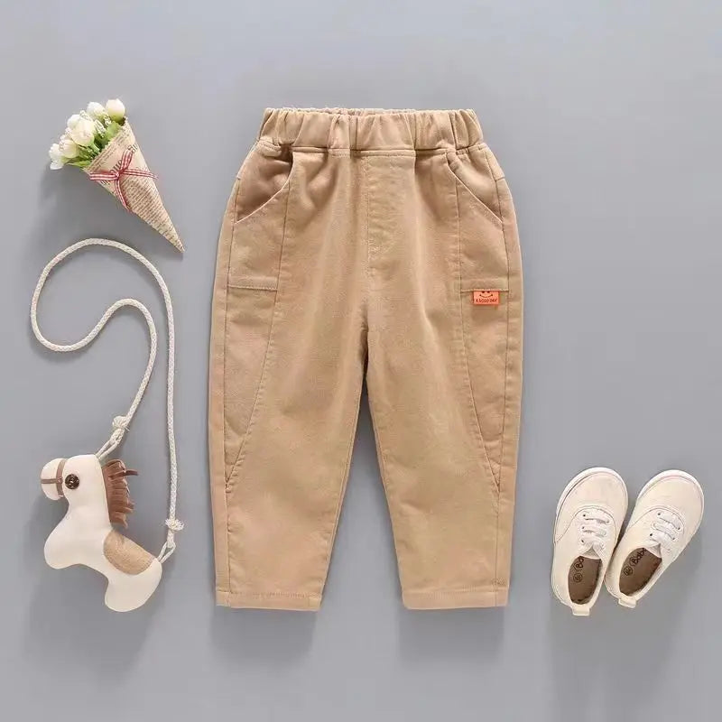 Beige children's pants with a toy horse and flower cone on a gray background