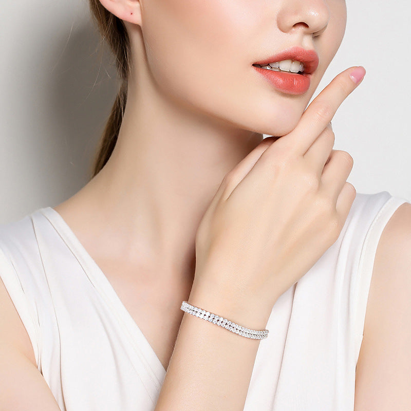 Woman wearing a silver bracelet on her wrist with a plain background