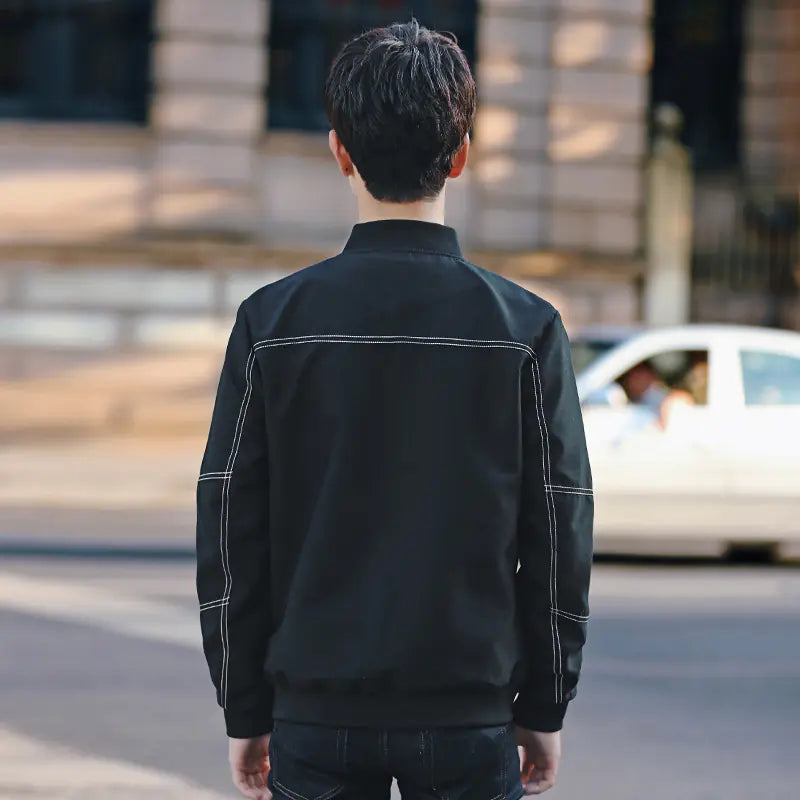 Person wearing a black jacket walking on a street with a blurred background