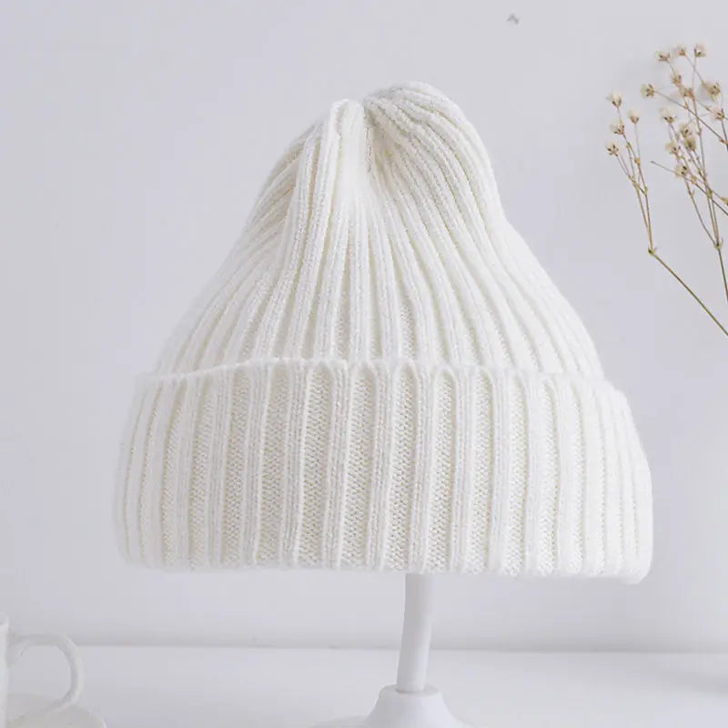 White knitted beanie on a white stand with a light gray background