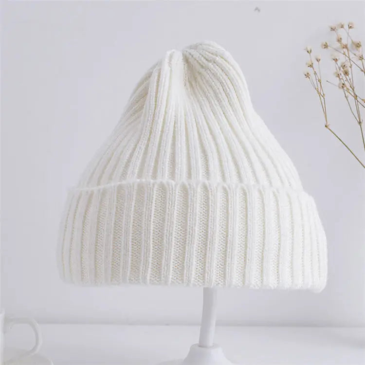 White knitted beanie on a white stand with a light gray background