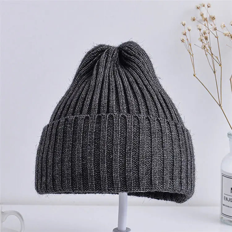 Gray knit beanie on a stand with a light gray background