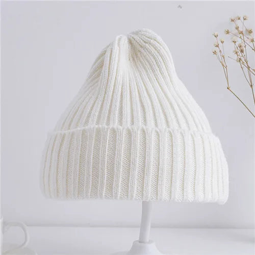 White knitted beanie on a white stand with a minimal background