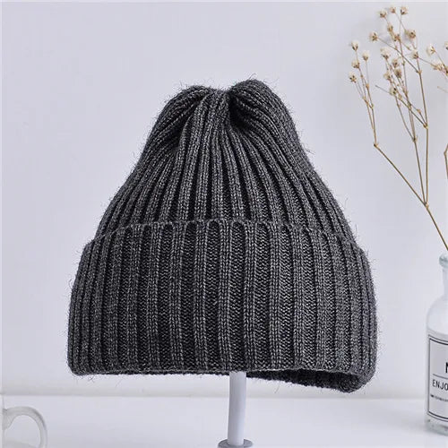 Gray knit beanie on a white stand with a light gray background