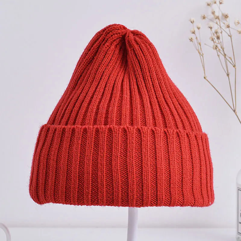 Red knitted beanie on a white stand with a light background