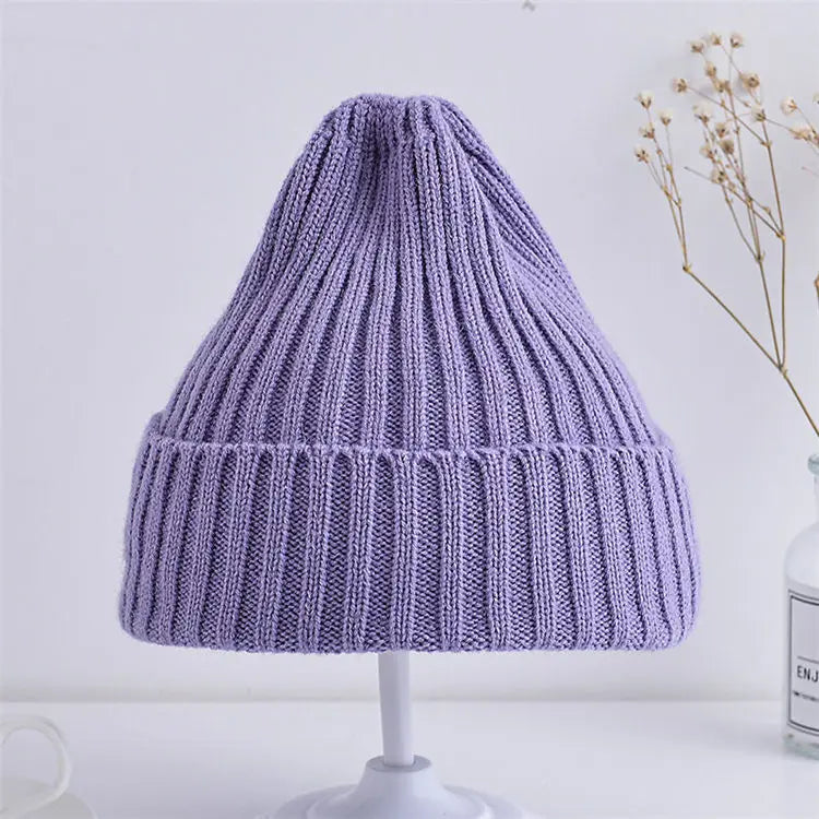 Purple knitted beanie on a white stand with a light background