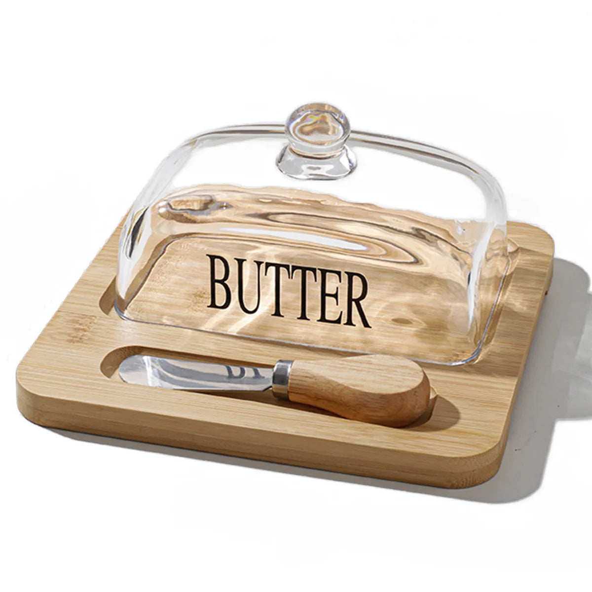 Butter dish with glass cover, wooden handle, and knife on a white background