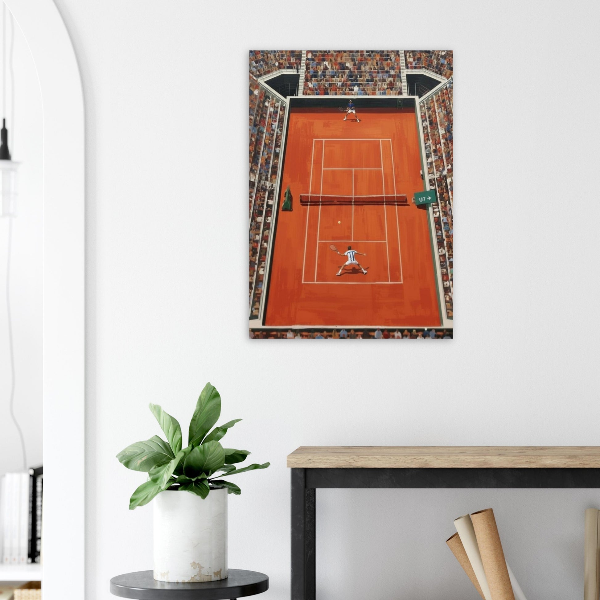 Framed artwork of a tennis court on a white wall above a desk with a plant.
