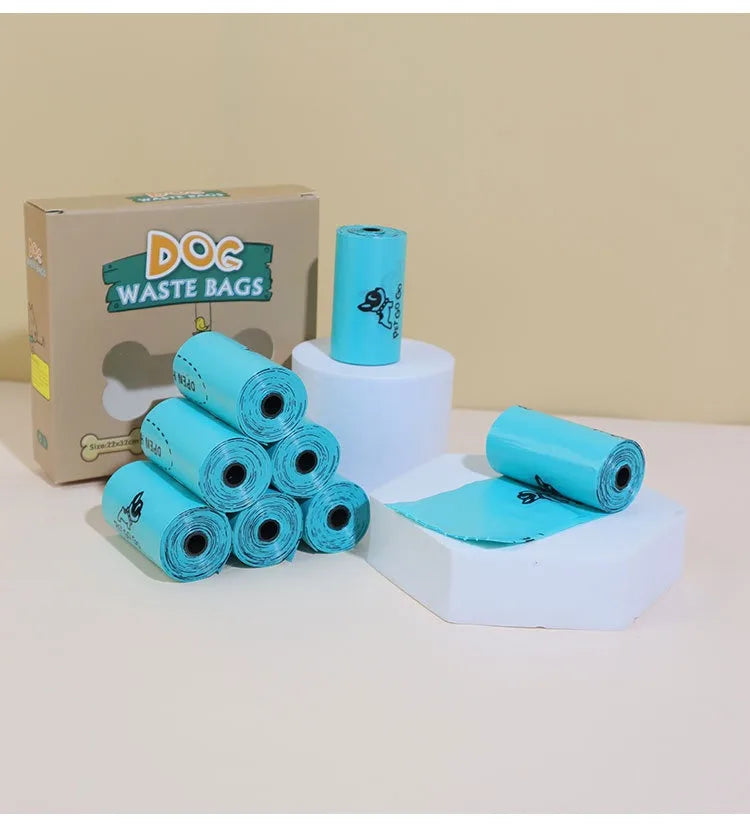 Rolls of blue dog waste bags with a cardboard box labeled 'DOC Waste Bags' on a beige background.