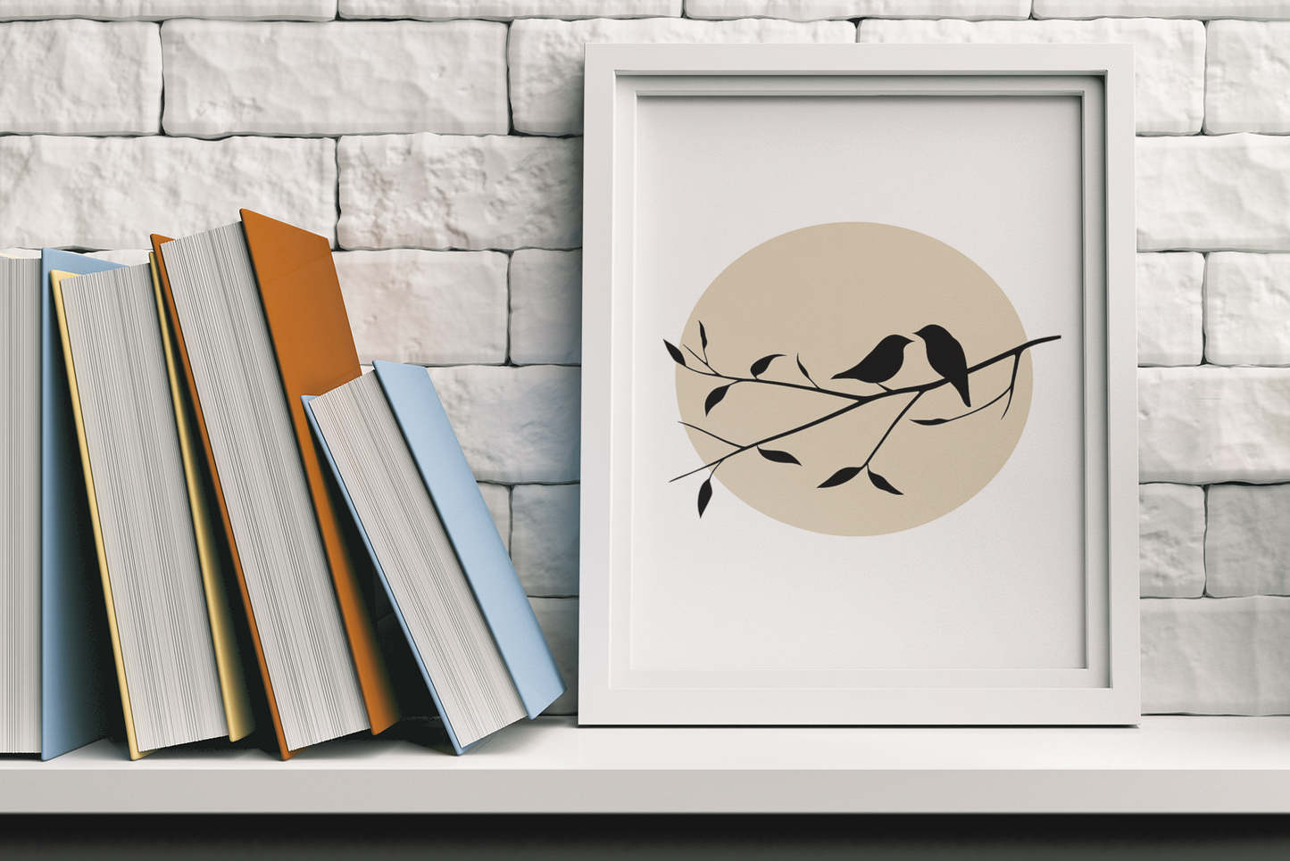 Framed bird silhouette poster with beige sun, resting on a white shelf next to stacked books against a white brick wall.