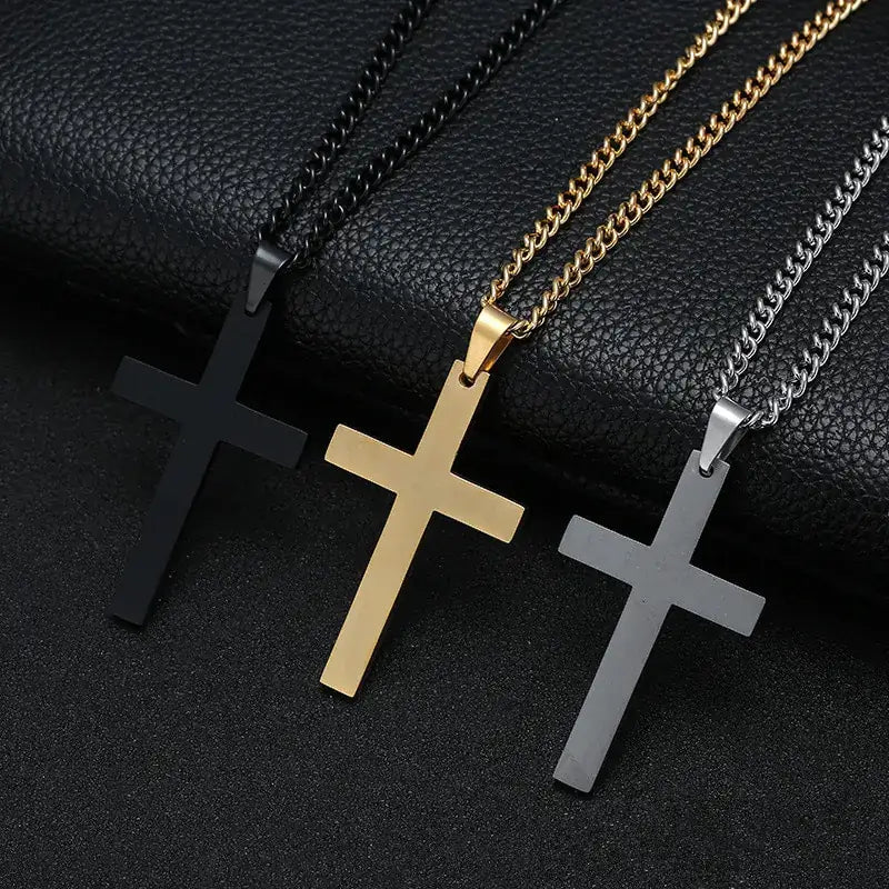 Three titanium cross necklaces in black, gold, and silver finishes displayed on a black textured surface with matching chain styles