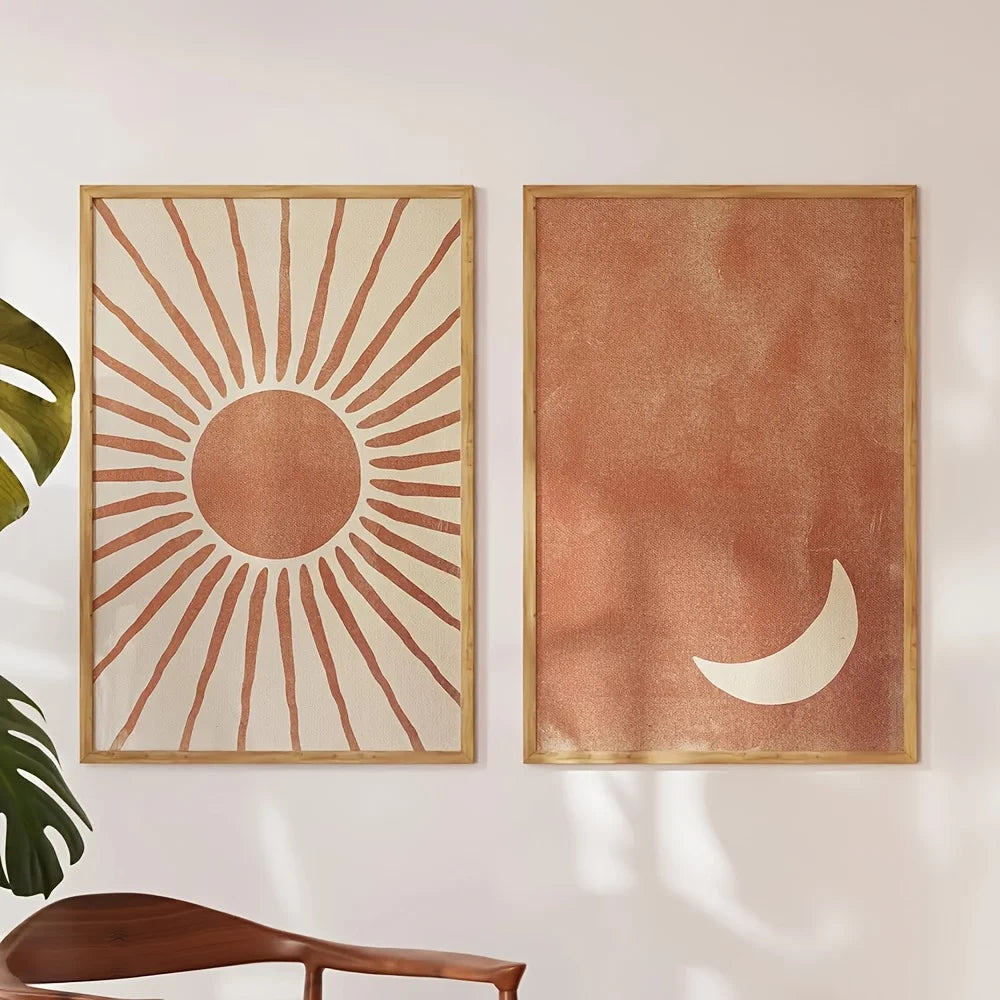 Two framed artworks of a sun and moon on a wall with a plant and chair in the foreground.