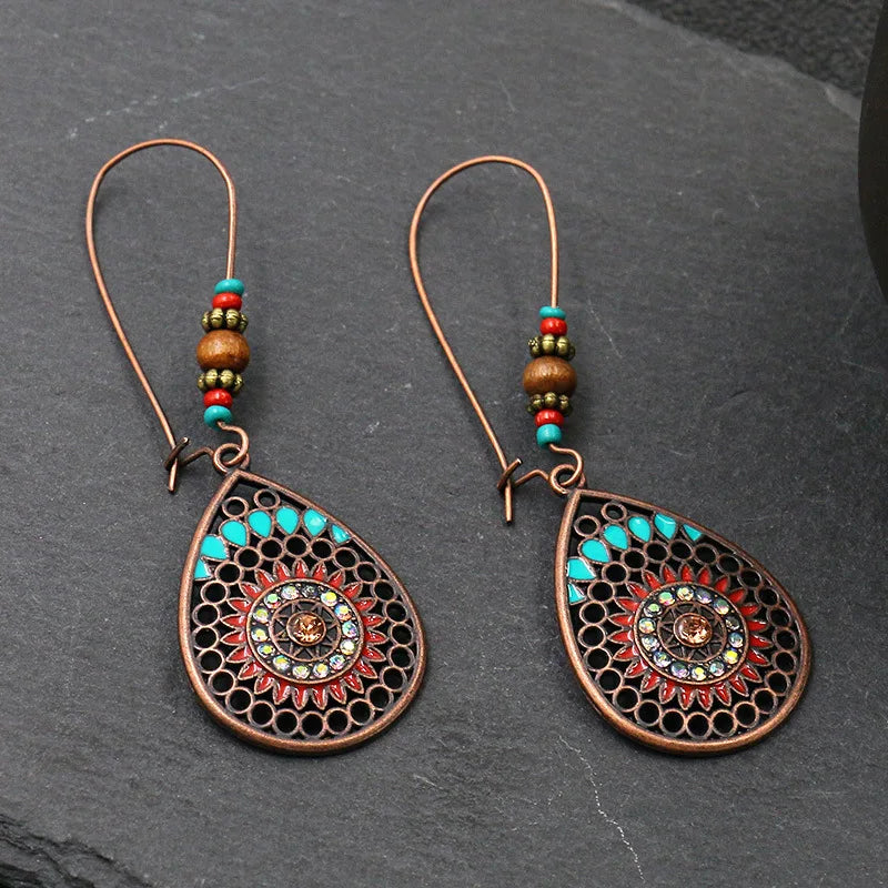 Pair of decorative earrings with intricate designs on a dark surface