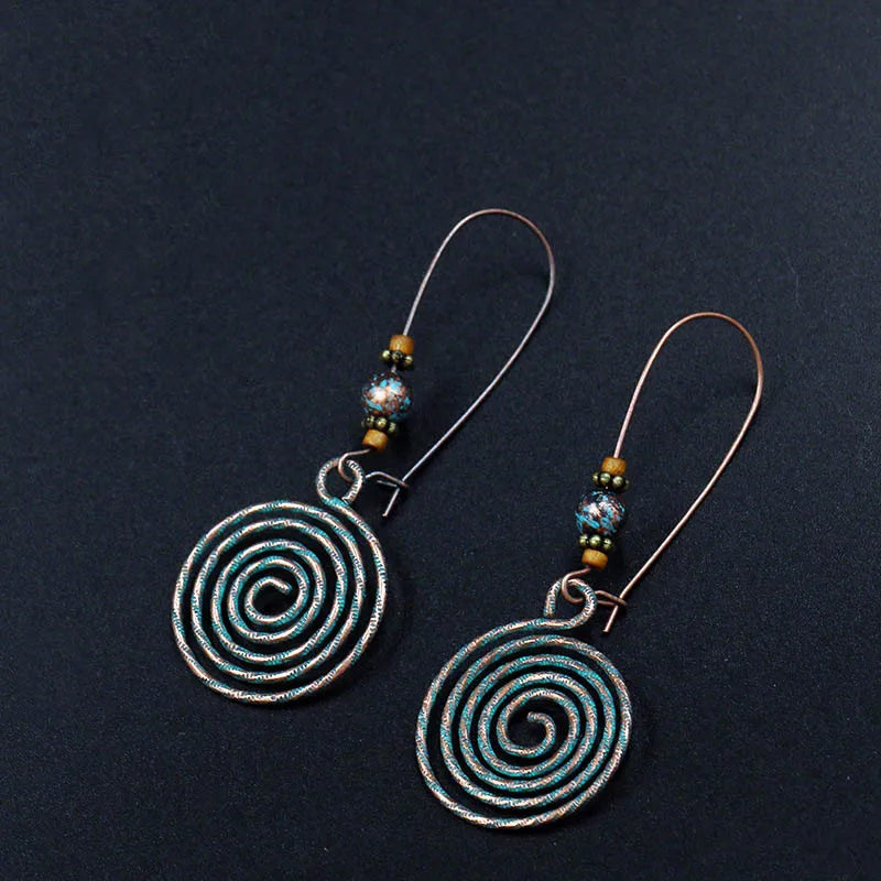 Spiral patterned earrings on a dark background