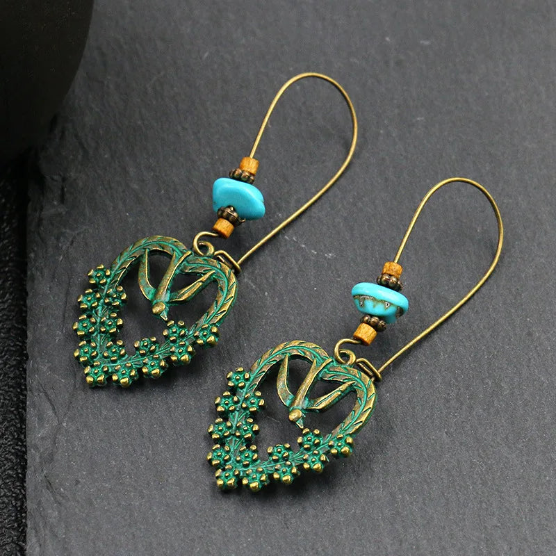 Pair of earrings with green and gold design on a dark gray background