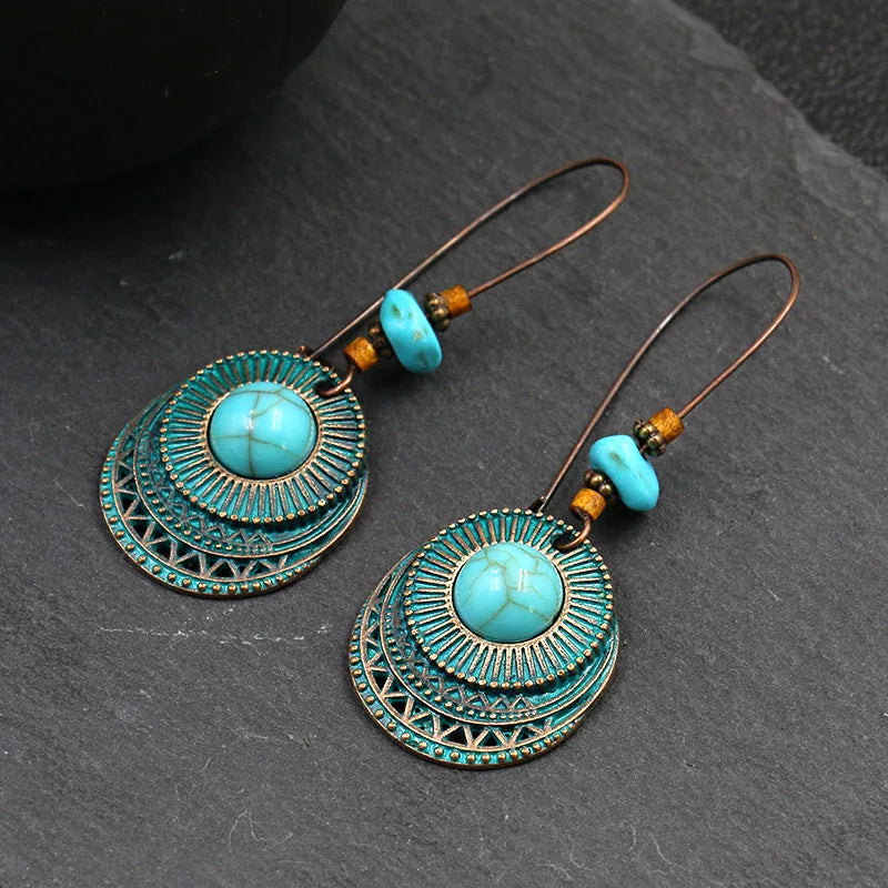 Turquoise earrings with intricate designs on a dark surface
