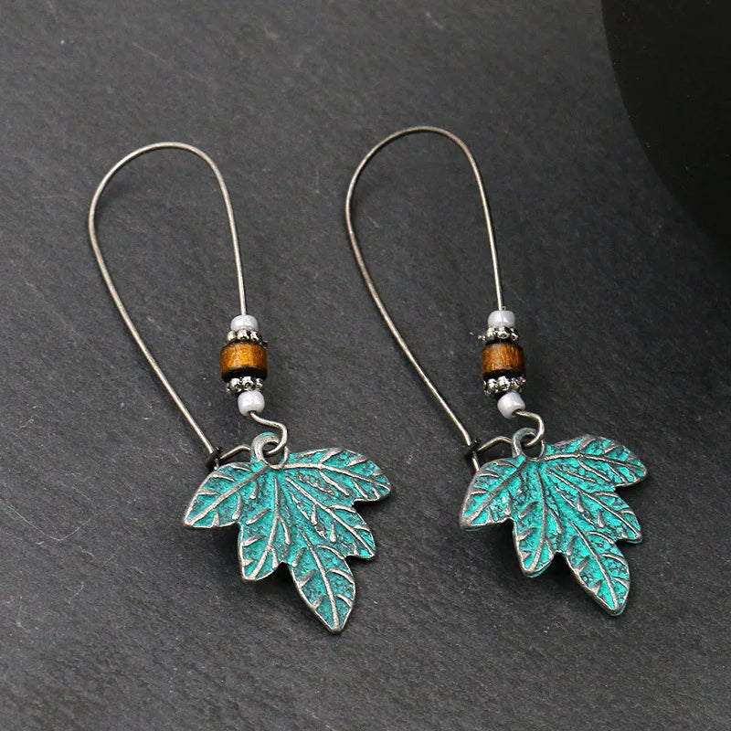 Pair of leaf-shaped earrings with turquoise finish on a dark gray background