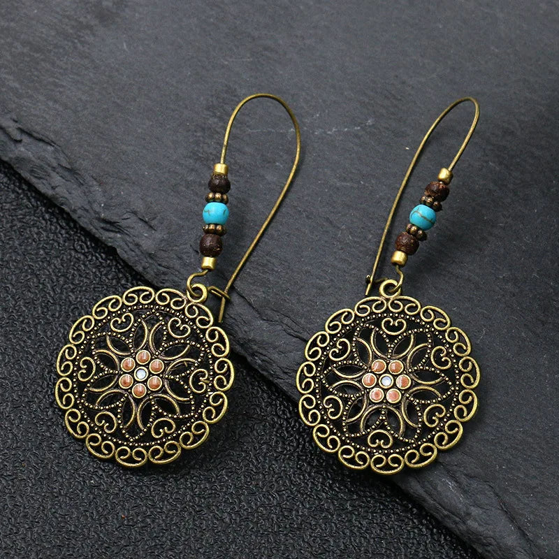 Pair of ornate earrings with decorative patterns on a dark surface