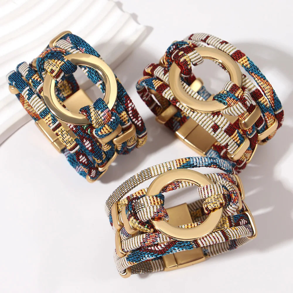 Three colorful woven bracelets with gold circular clasps on a white background