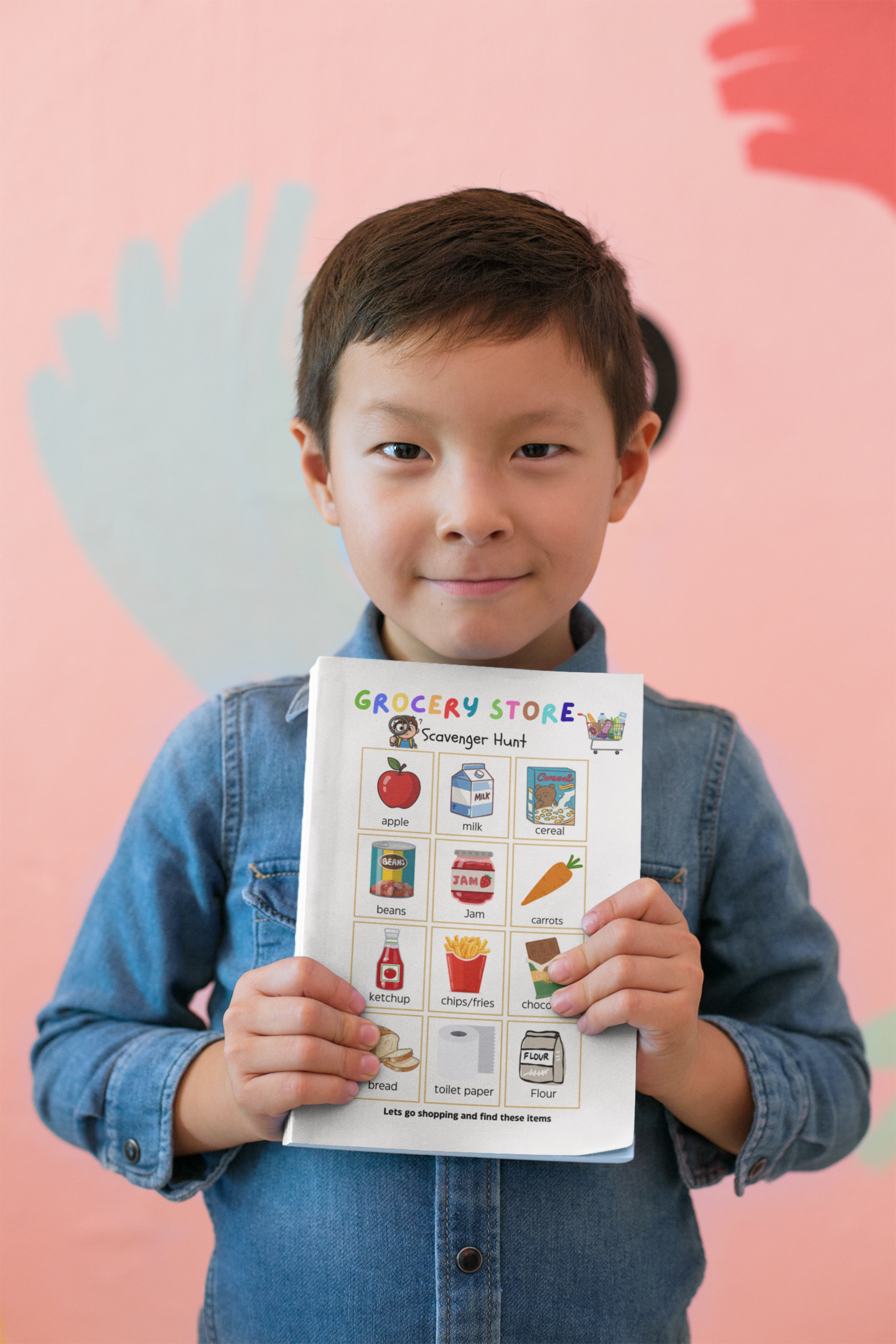 Child holding a grocery store-themed learning chart against a pink background