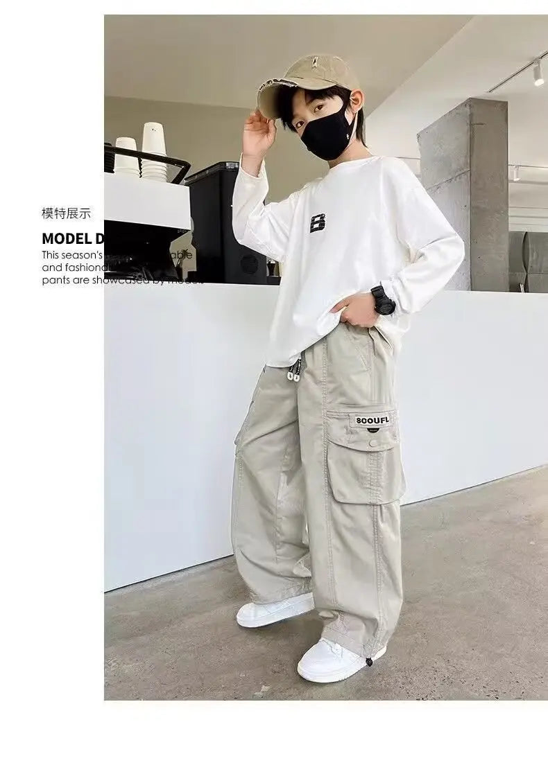 Person wearing a white sweatshirt, beige cargo pants, and a black face mask in an indoor setting.