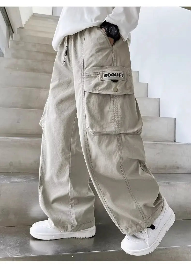 Person wearing beige cargo pants with a brand logo on a staircase.