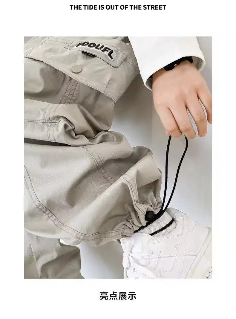 Person wearing beige pants with a brand logo, holding a black cord.