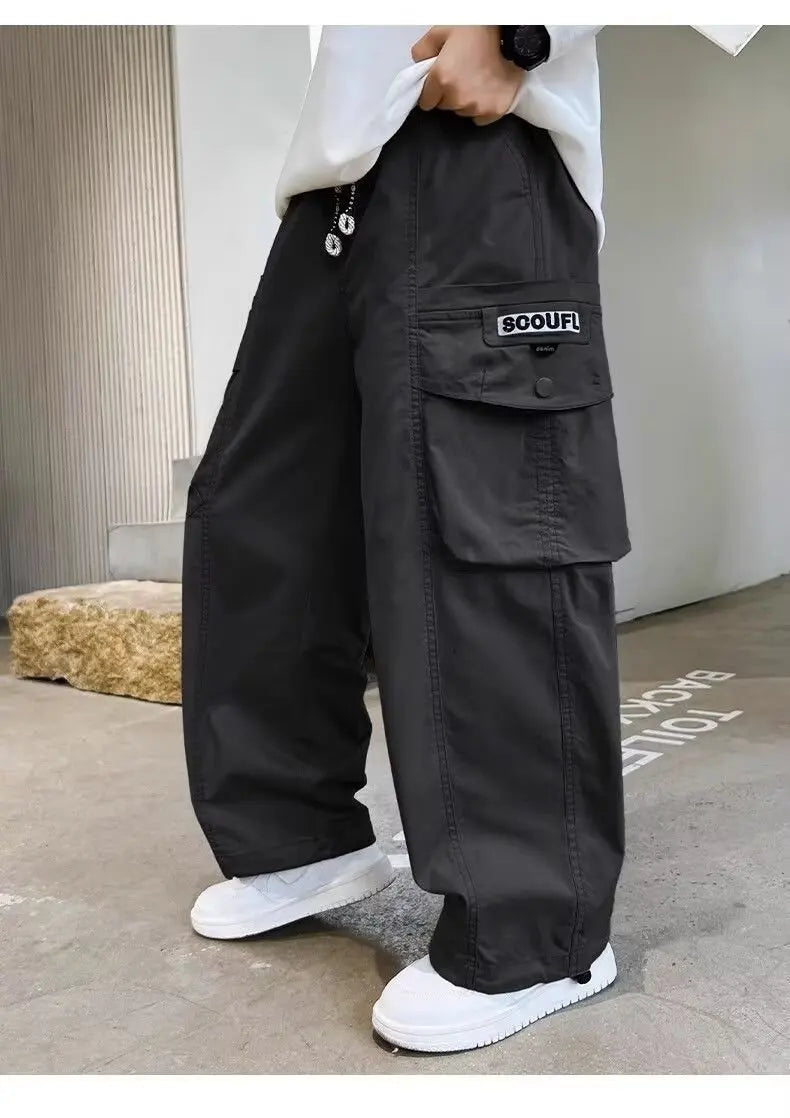 Person wearing black cargo pants with a visible brand logo, standing indoors.