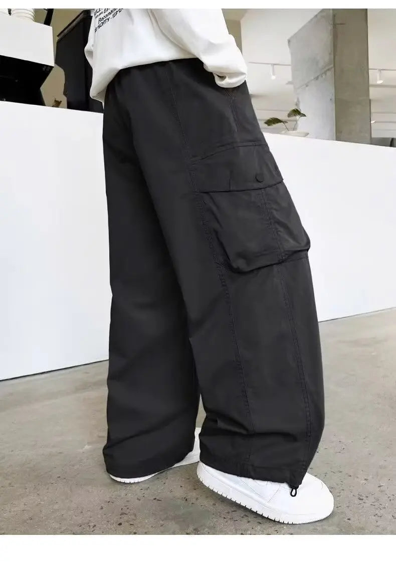 Person wearing black cargo pants with a white background