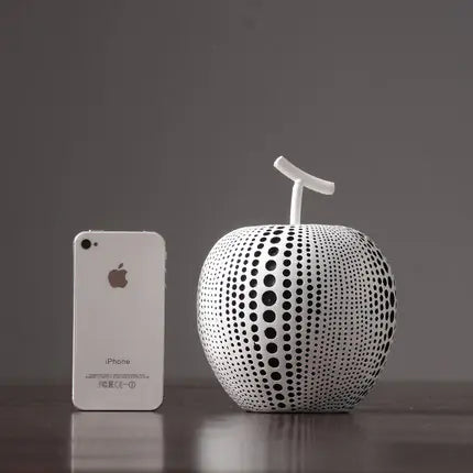 Phone next to a unique apple-shaped object with a black and white pattern on a dark surface.